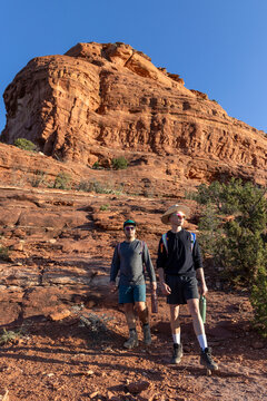 Two male friends hike together in a desert canyon