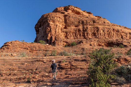 Hiker looks up at a massive red rock formation