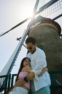Father and daughter posing by a traditional Dutch windmill