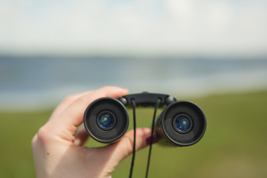 Woman holding black binoculars in nature with copy space
