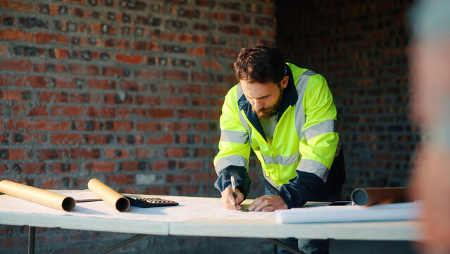 Construction site, writing and man with blueprint for planning, layout and building measurements. Civil engineer, architecture and person with paper for renovation design, evaluation and dimensions