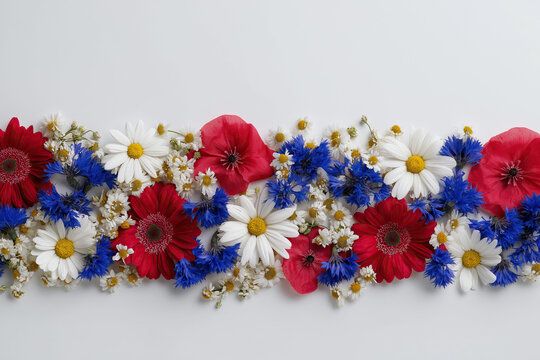 An overhead flat-lay arrangement of red poppies white daisies and blue cornflowers celebrates patriotic summer holidays.