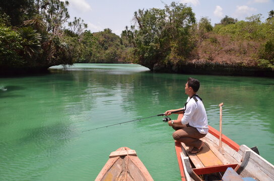 Man fishing in turquoise Lake Napabale Muna Southeast Sulawesi Indonesia
