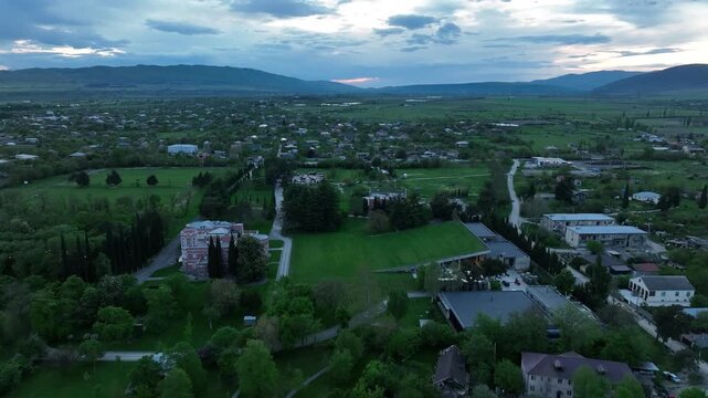 Aerial view of Chateau Mukhrani royal palace and estate in Georgia, magnificent pink castle architecture with a tower surrounded by a lush green park, gardens and pathways on a spring day.