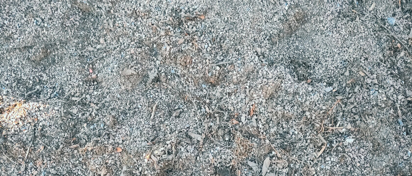 High-angle background shot of natural grey crushed stone aggregate mixed with dry organic debris, dirt, and small twigs. Perfect for construction, landscaping, gardening, or textured abstract backgrou