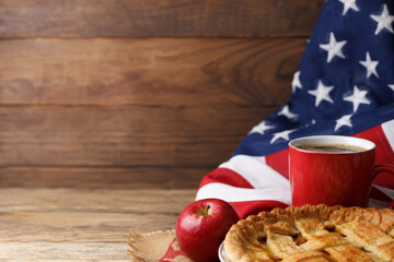 American culture concept with apple pie, coffee mug and US flag on wooden background. USA independence day celebration.