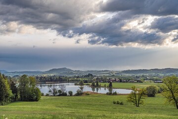 Naklejka premium Dramatic Stormy Weather Clouds Over Oeschlesee Lake Near Durach, Allgaeu Landscape with Stoffelberg Mountain in the Background, Germany