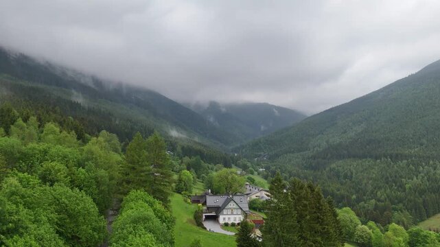 Aerial view of a misty mountain valley with spruce forest and scattered cottages in Krkono&scaron;e Czech Republic