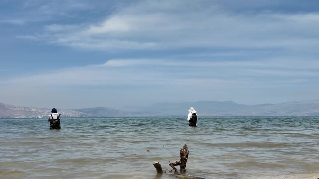 fishermen on shores of Sea of Galilee or lake Kineret with Tiberias in the background in northern Israel