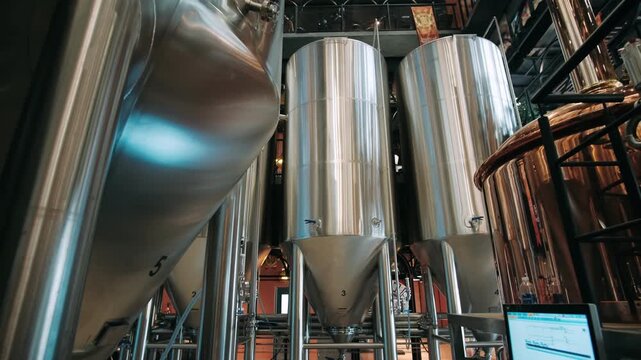 Steel fermentation tanks and pipes inside a modern craft beer brewery for alcohol beverage production