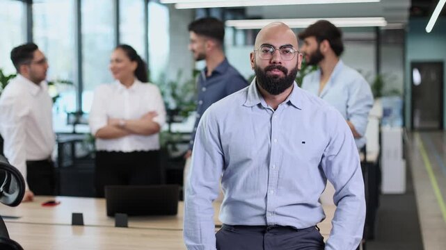 A man with a beard and glasses is posing for a picture with a group of people