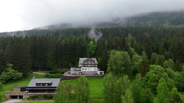 Aerial view of mountain house in misty spruce forest in Krkono&scaron;e Mountains Czech Republic
