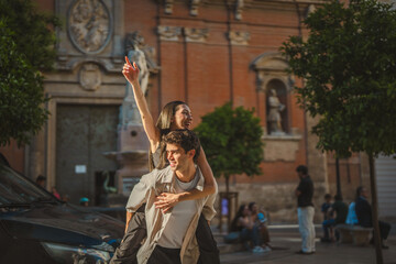 Obraz premium Happy joyful couple enjoying piggyback ride in city