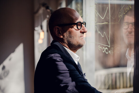 senior businessman brainstorming, drawing formulas on window pane