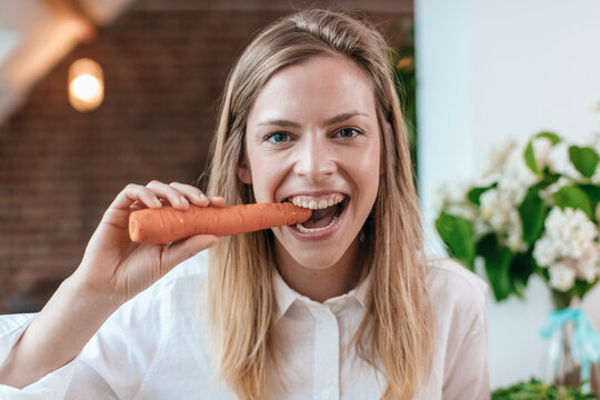 Portrait of young woman biting carrot