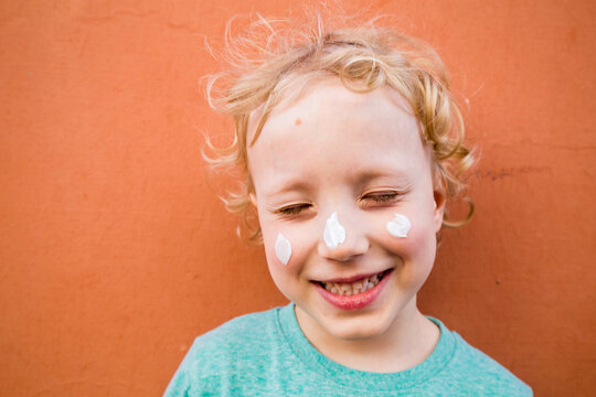 Portrait of smiling little boy with three blobs of cream on his face