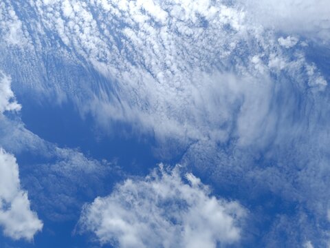 Variety of cloud formations against a deep blue sky. Textured cirrocumulus wispy cirrus and fluffy cumulus clouds