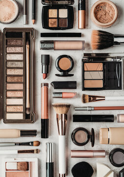 Flat lay of various makeup and cosmetic products on stone backdrop