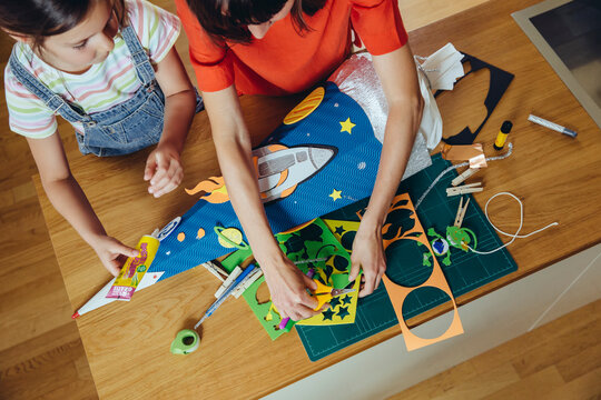 Mother and daughter creating her space themed school cone at home