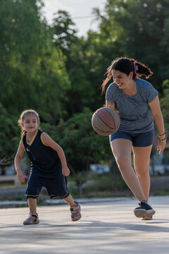 Mother and daughter playing basketball outdoors