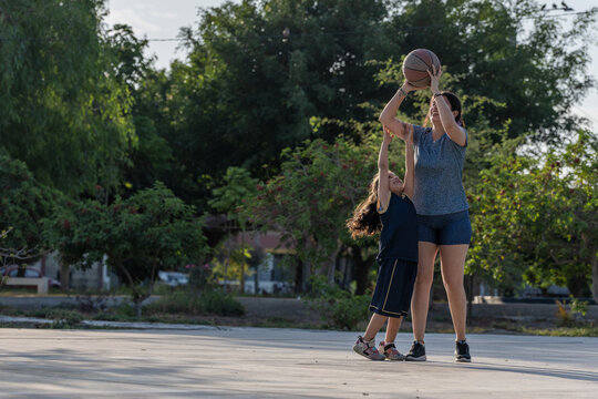Mother and daughter playing basketball outdoors together