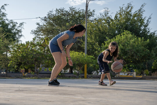 Mother and daughter playing basketball outdoors