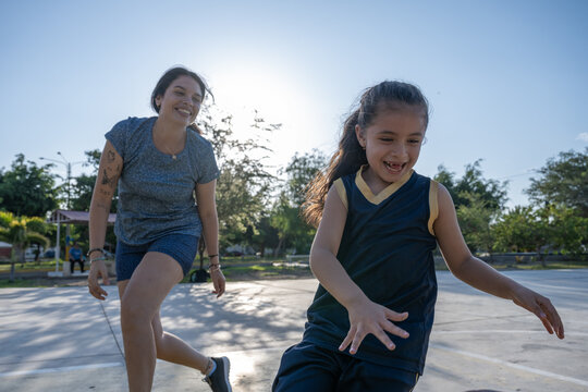 Mother and daughter playing basketball outdoors