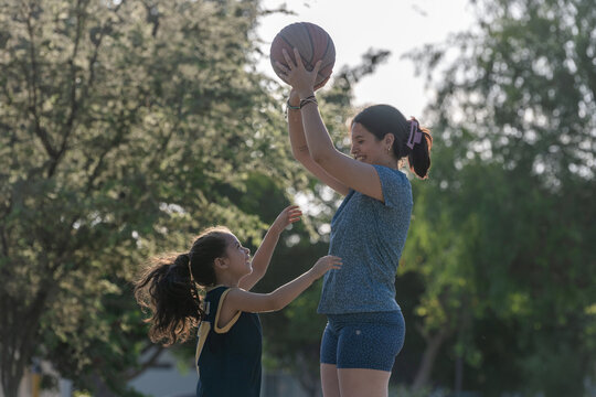Mother and daughter playing basketball outdoors