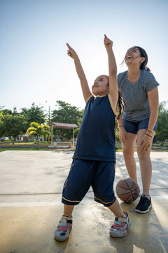 Mother and daughter playing on outdoor basketball court