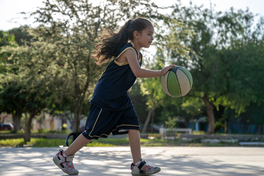 Young girl dribbling basketball on outdoor court