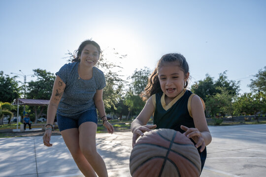 Mother and daughter playing basketball outdoors