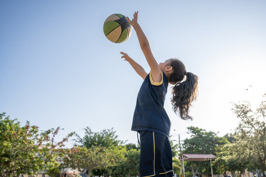 Young girl reaching for basketball outdoors