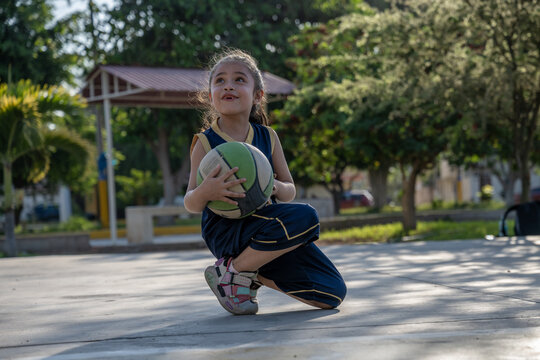 Hopeful young girl with basketball at the park