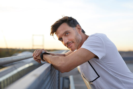 Confident athlete leaning on railing