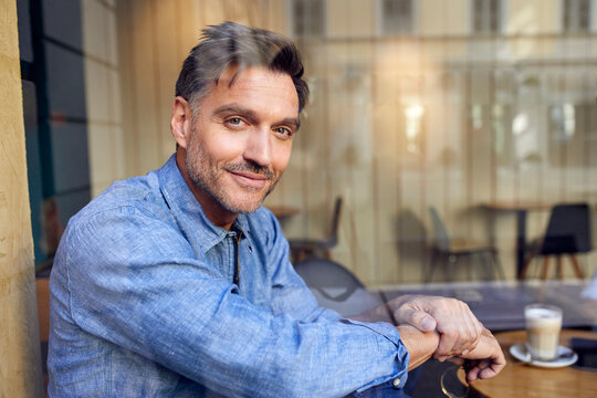 Portrait of confident man behind windowpane in a cafe