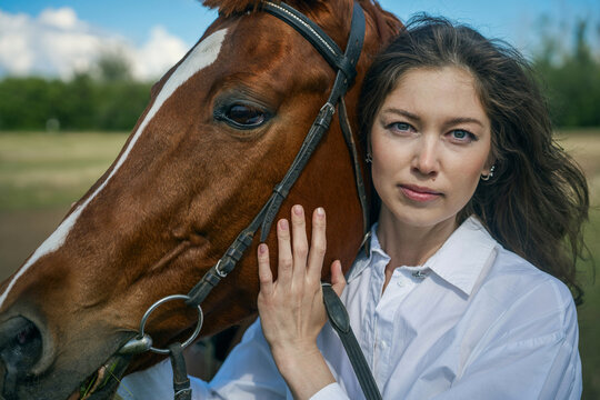 Young woman and horse in a field, blue sky