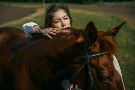 Young woman and horse in a field, blue sky