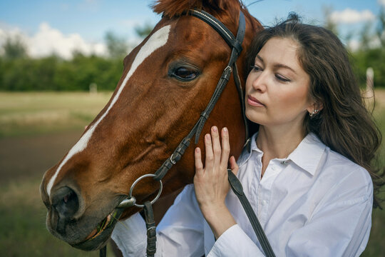 Young woman and horse in a field, blue sky