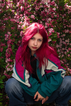 Girl with pink hair crouching by flowers, retro style