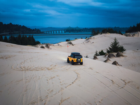 Off road vehicle explores Oregon sand dunes at dusk