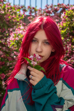 Teenage girl with bright red hair holds pink flowers