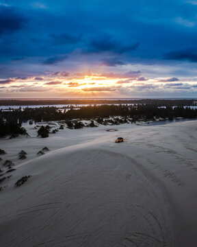 Off road vehicle on a vast sand dune at sunset