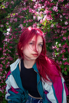 Young girl with windblown red hair by pink flowers