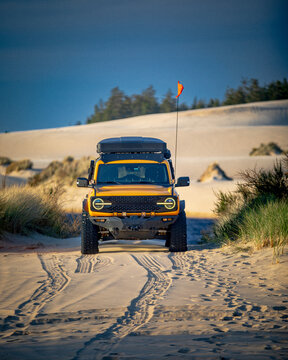 Yellow off road vehicle driving on a sand dune trail