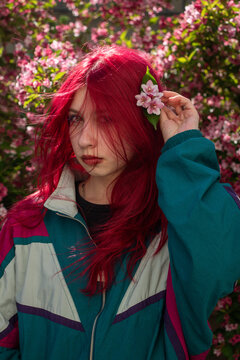 Young woman putting a pink flower in red hair