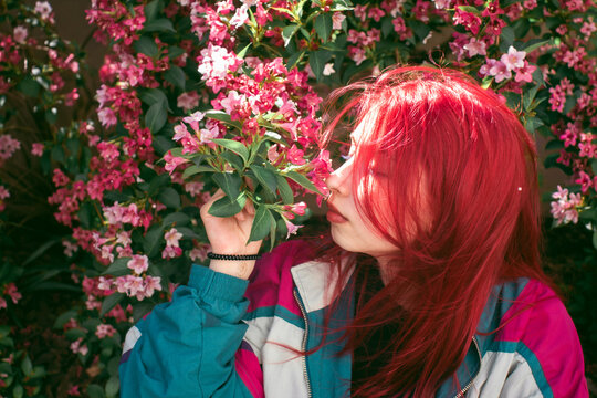 Young woman with red hair smelling pink flowers, retro style