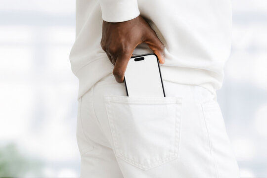 Black man putting smartphone in his back pocket