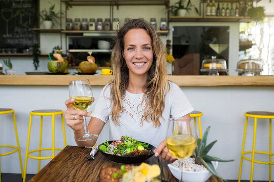 Portrait of smiling woman holding glass of wine in a cafe