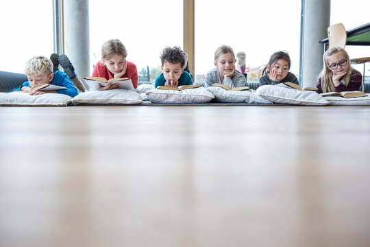 Students relaxing on the floor with books during their school break in the common room
