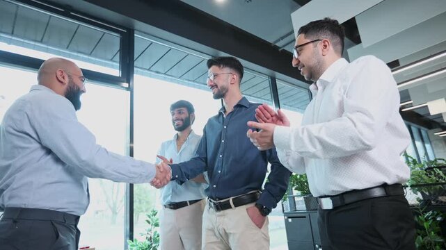 A group of people are shaking hands and smiling in a business setting